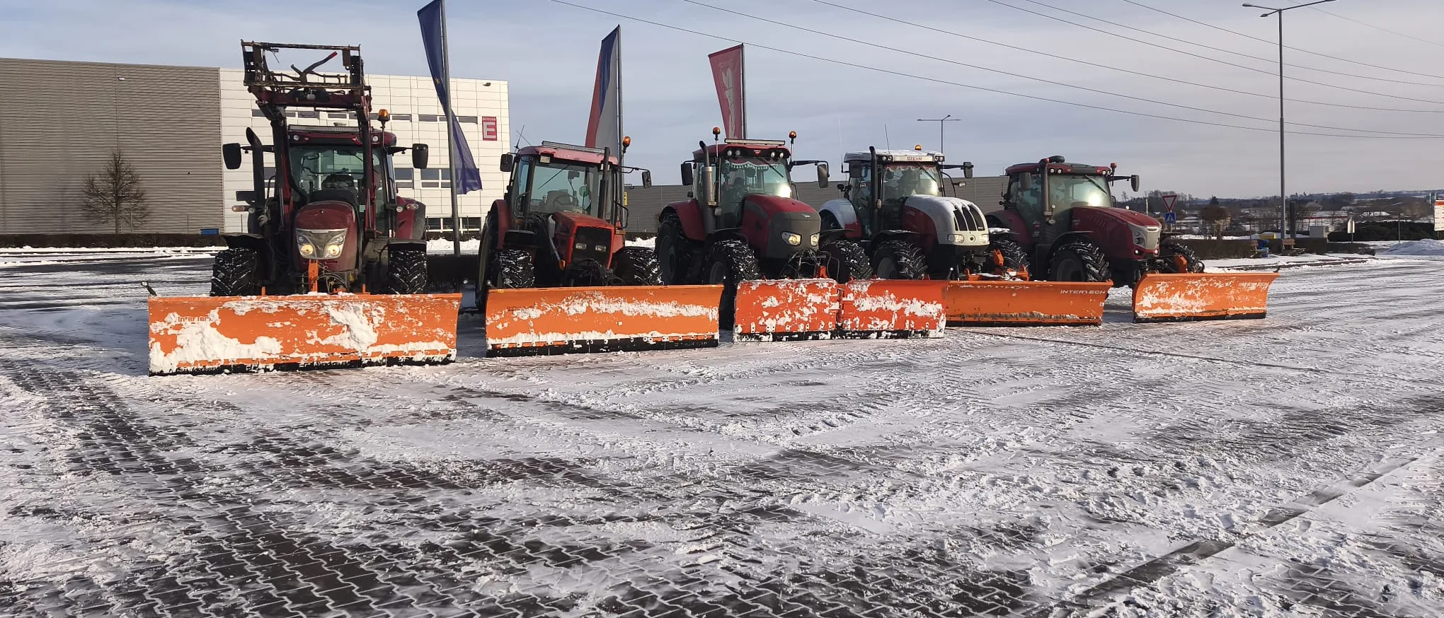 Traktory s radlicemi připravené na zasněženém parkovišti